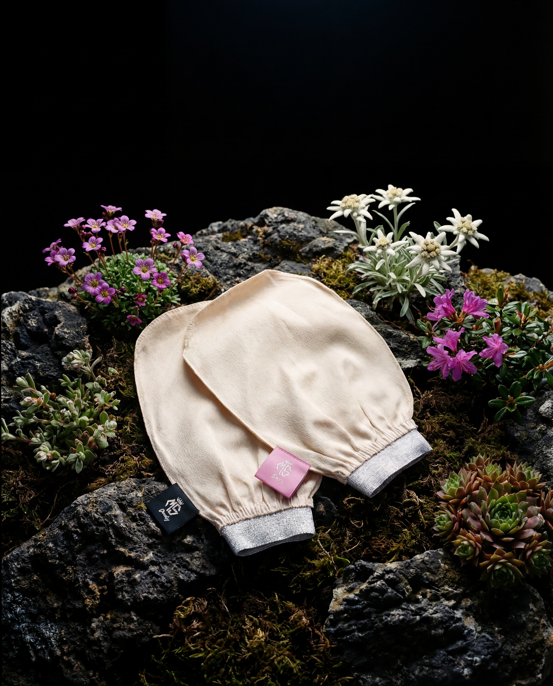Moroccan silk exfoliating gloves resting on mossy rocks with flowers